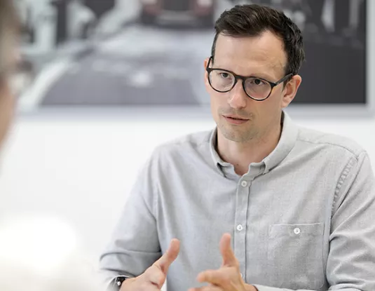 Man with glasses talking to colleague in office