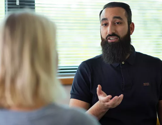 British Asian man talks to female colleague in office